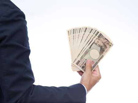 Hand holding Japanese banknote on white background. Japanese money.の写真素材