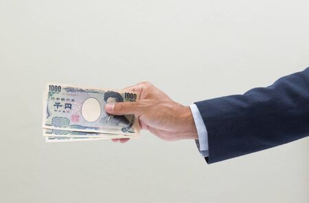 Businessman hand holding Japanese YEN banknote