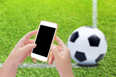 Hand holding smartphone with soccer ball on play fieldsの写真素材