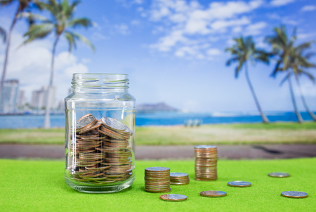 Coins in glass bottle with blur Hawaii island backgroundの写真素材
