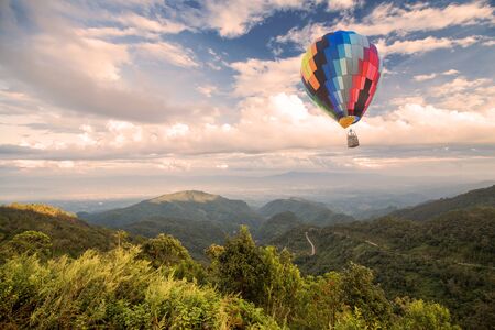 Hot air balloon over forest mountain and blue skyの写真素材