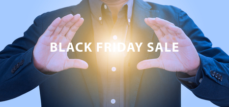 Businessman hands grabbing Black friday sale with abstract lightの写真素材