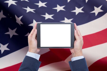 Man hands holding digital tablet computer with United state of america flag backgroundの写真素材