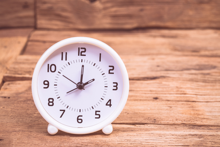 Clock on old wood table with vintage color effected 