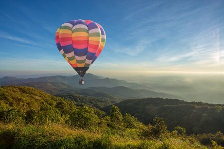 Colorful hot air balloon over the mountain at sunsetの写真素材