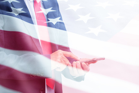 Double exposure of unrecognizable Businessman hand holding smartphone with United state of America flagの写真素材