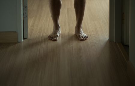 Male legs standing at the door with window light from backsideの写真素材