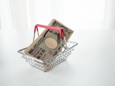 Japanese Yen in shopping basket on white backgroundの写真素材