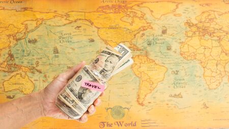 Man hand holding bottle of saving travel money with world map backgroundの写真素材