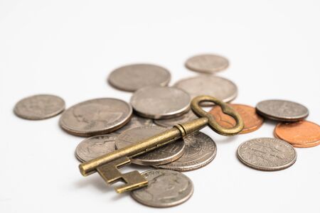 Old vintage brass key with coins on white backgroundの写真素材