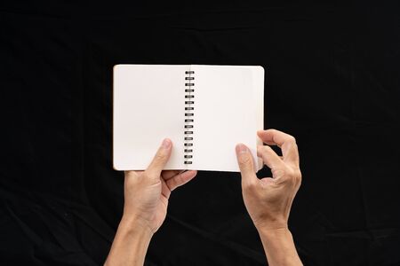 Man hand holding blank notebook on black backgroundの写真素材