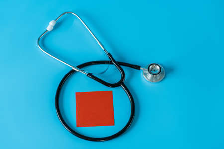 Stethoscope and red adshive note on blue background. Medical and health care conceptの写真素材