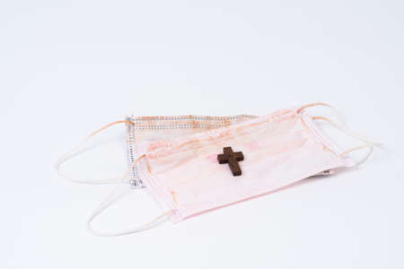 Used face mask and wood cross