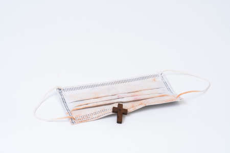 Used face mask and wood cross