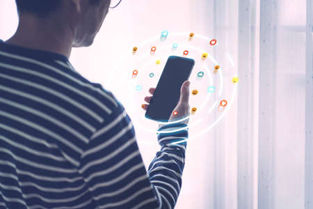 Back side of man using mobile phone with Social media emoji icons graphic popup