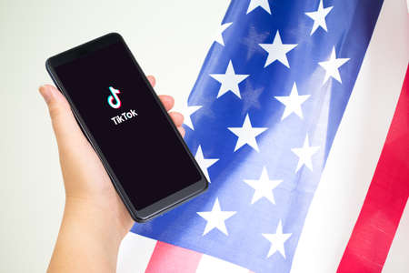 Chiang mai, Thailand - 16 August, 2020 : Close up of Hand holding smartphone with TikTok application with US or American flag as background and copy space.のeditorial素材