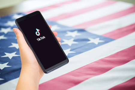 Chiang mai, Thailand - 16 August, 2020 : Close up of Hand holding smartphone with TikTok application with US or American flag as background and copy space.のeditorial素材