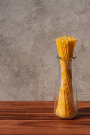 Spaghetti in a glass bottle on a wooden table. Selective focus.の写真素材