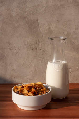 A bottle of milk and a bowl of cornflakes on a wooden tableの写真素材