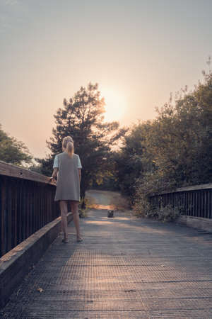 girl walking on wooden bridge. Tranquility at sunset.の写真素材