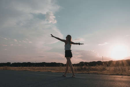 blonde-haired woman walking on the road at sunset in shortsの写真素材