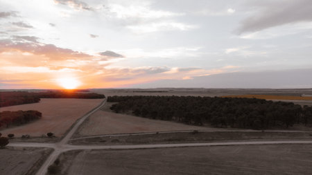 drone view of sunset in the middle of the countryside with dirt roads and treesの写真素材