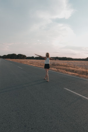 blonde-haired woman walking on the road at sunset in shortsの写真素材