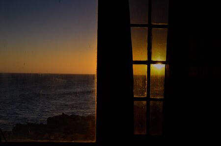 sunset in the ocean through a windowの写真素材