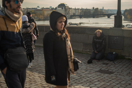 Prague, Czech Republic. 01-11-2020. Tourists are walking on the Charles Bridge on the Historical town in Prague. Beggar receiving indeference from tourists.のeditorial素材