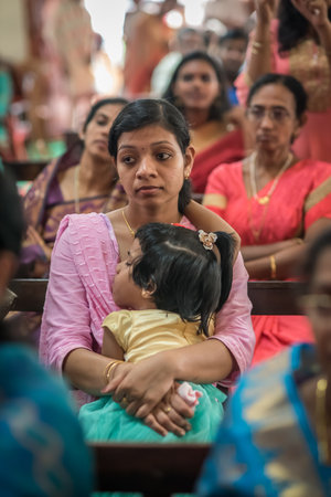 Kerala, India, 08-12-2017. Mother with sleeping child during ceremony. Catholic wedding in the Province of Kerala in South India. Religious celebration at church.のeditorial素材