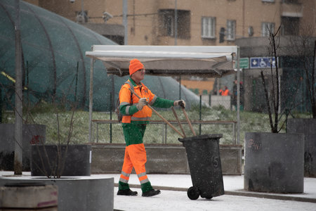 Prague, Czech Republic. 01-12-2021. Garbage collector worker walking on a snowing day with mask during covid-19 from hradcanska tram station at Prague 6のeditorial素材