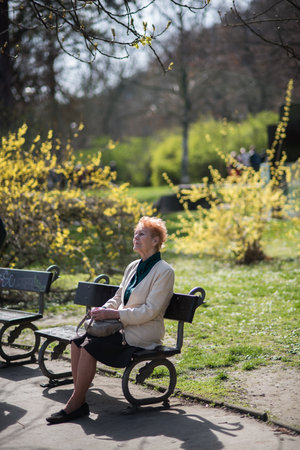 Prague, Czech Republic. 09-23-2019. Old woman sitting on a bench enjoying and relaxing during a sunny day in the city center of Prague.のeditorial素材