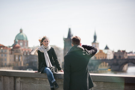 Prague, Czech Republic. 09-23-2019. Young man is photographing his girlfriend while walking and enjoying on the Charles Bridge during a sunny day in Prague.のeditorial素材