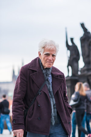 Prague, Czech Republic. 09-23-2019. Old man walking and enjoying on the Charles Bridge during a sunny day in Prague.のeditorial素材