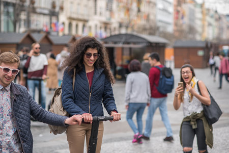 Prague, Czech Republic. 09-23-2019. Young friends are walking smiling and enjoying with a scooter on the city center of Prague, during a sunny day.のeditorial素材