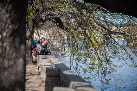 Prague, Czech Republic. 09-23-2019. Beautiful and fashion young woman taking a rest below some trees enjoy walking during a sunny day in the city center of Prague.のeditorial素材