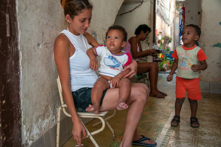 La Havana, Cuba. 04-15-2018. Mother smoking while holding her child at her house in La Havana, Cuba during a sunny day.のeditorial素材