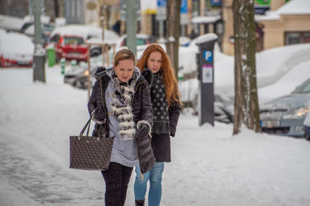 Prague, Czech Republic. 02-08-2021. Mother and daughter walking and talking in the city center of Prague on a cold winter snowy day.のeditorial素材