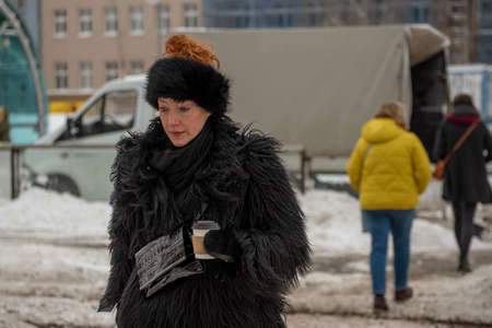 Prague, Czech Republic. 02-08-2021. Beautiful and elegant woman with a coffee is walking in the city center of Prague on a cold winter snowy day.のeditorial素材