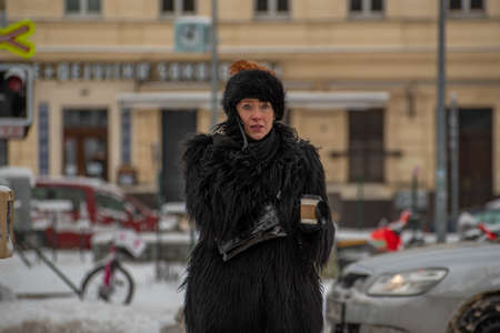Prague, Czech Republic. 02-08-2021. Beautiful and elegant woman with a coffee is talking on her cellphone while walking in the city center of Prague on a cold winter snowy day.のeditorial素材