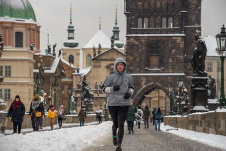 Prague, Czech Republic. 02-08-2021. Young runner on the Charles Bridge in the city center of Prague on a cold winter snowy day.のeditorial素材