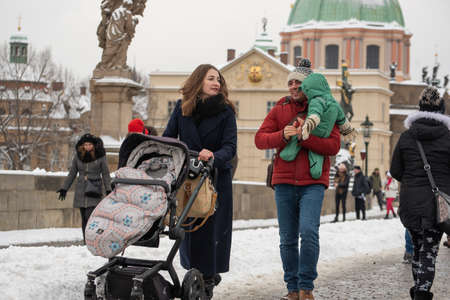 Prague, Czech Republic. 02-08-2021. Mother, husband and child walking on the Charles Bridge in the city center of Prague on a cold winter snowy day.のeditorial素材