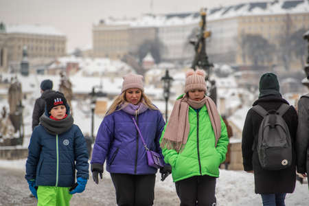 Prague, Czech Republic. 02-08-2021. Mother with two kids walking and talking on the Charles Bridge in the city center of Prague on a cold winter snowy day.のeditorial素材