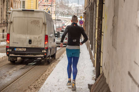 rague, Czech Republic. 02-08-2021. Young runner in the city center of Prague on a cold winter snowy...
