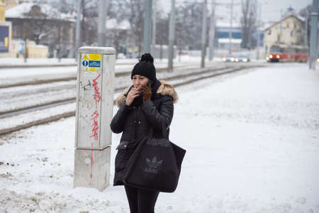 Prague, Czech Republic. 02-08-2021. Smoking woman is waiting for the tram in the city center of Prague on a cold winter snowy day.のeditorial素材