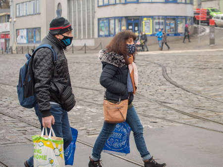 Brno, Czech Republic. 02-17-2021. Man and woman migrants with face mask to protect from corona virus walk on Halvni Nadrazi main tram station in the city center of Brno during a cold winter day.のeditorial素材