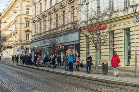 Brno, Czech Republic. 02-17-2021. People with face mask to protect from corona virus walk on Cheska tram stop in the city of Brno on cold winter day.のeditorial素材