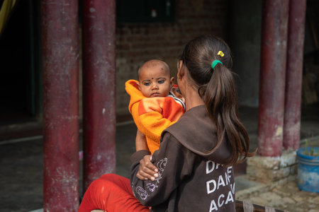 Uttar Pradesh. 05-15-2018. Young girl holding a baby at her house in a rural village of India.のeditorial素材