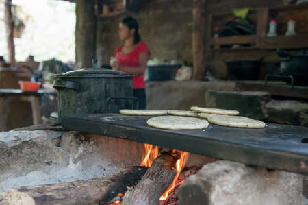 Suchitoto, El Salvador. 06-25-2016. Mother cooking at the house where they live. People living in a rural areas of the country, relying on raising cattle and cultivate vegetables for survival.のeditorial素材