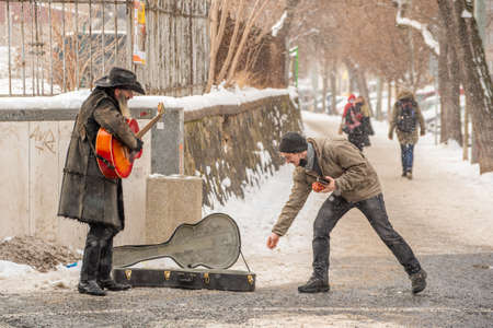 Prague, Czech Republic. 02-23-2021. Street musician singing and playing guitar receiving money from...